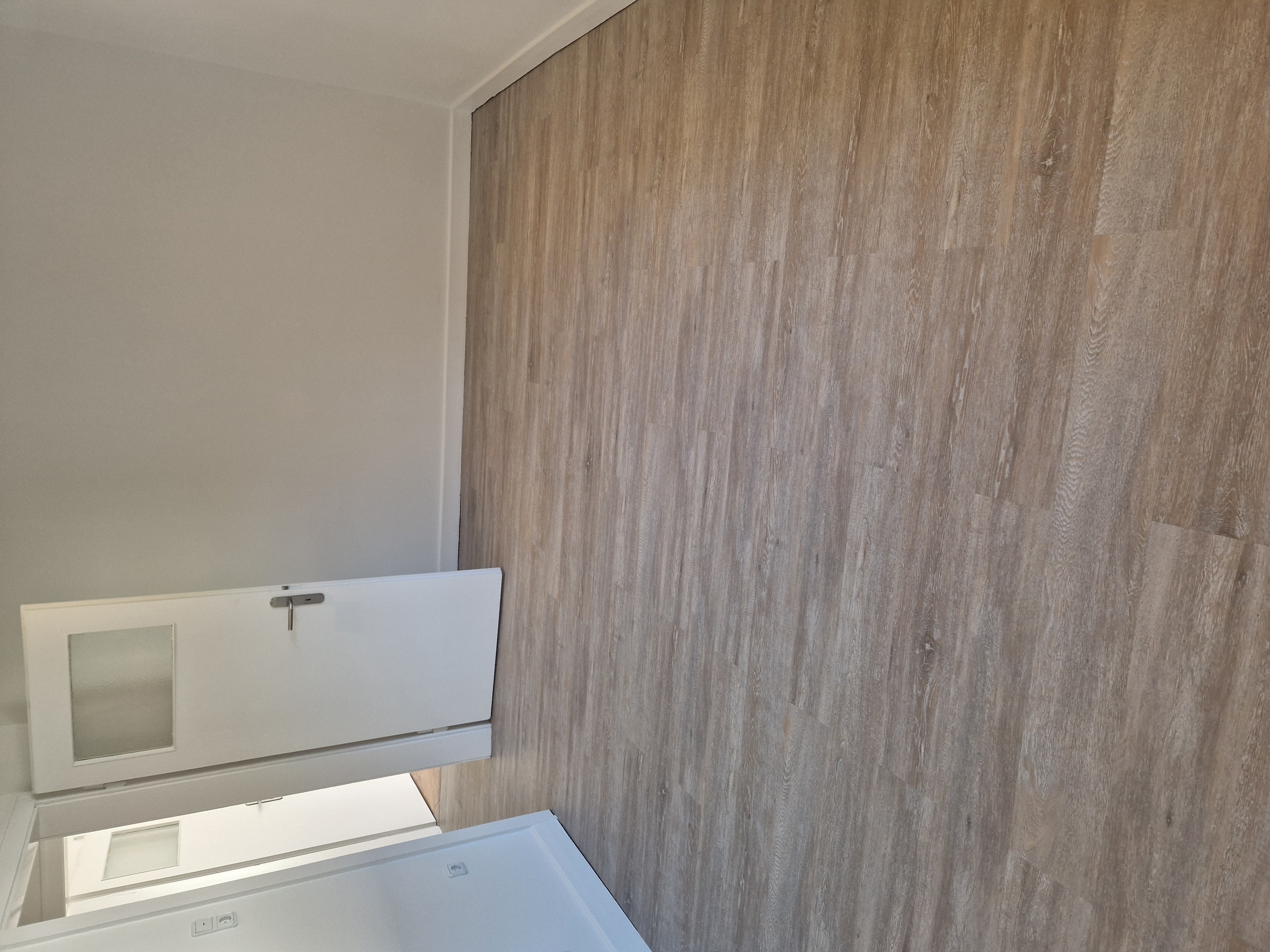 Renovierter Raum mit fertig verlegtem grauem Boden und weißen Fußleisten
